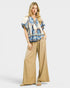 Beach Rose Co. Ivory and blue paisley border print rayon top with tassel details and tie neck. Relaxed fit, short sleeves.