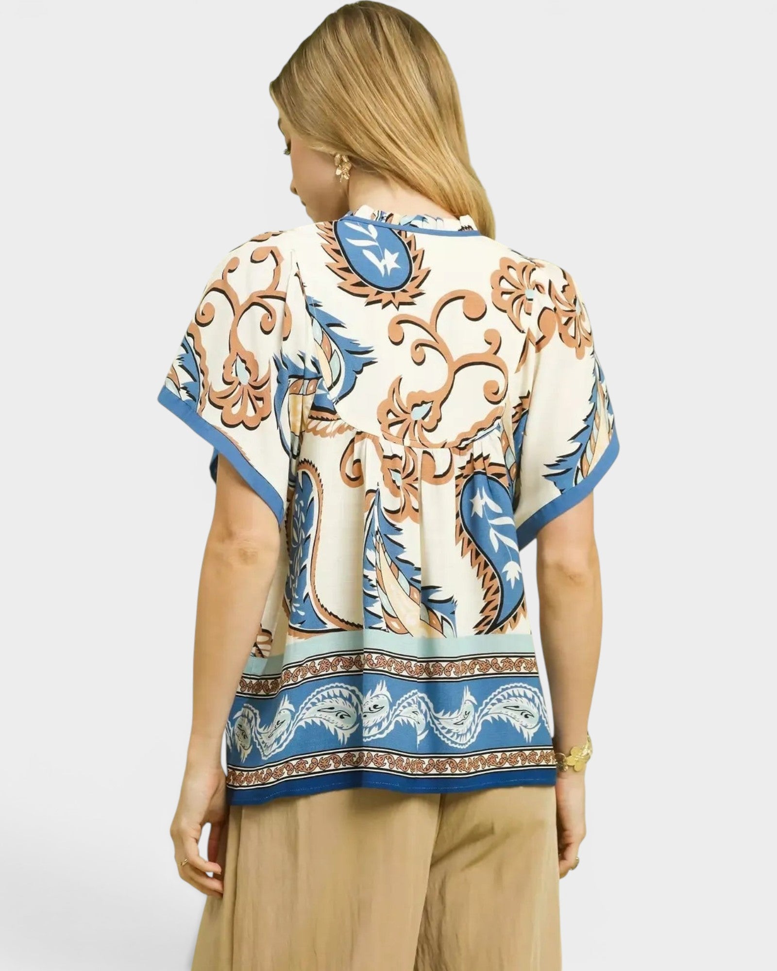 Beach Rose Co. ivory and blue paisley border print rayon top with tassel details and flutter sleeves.