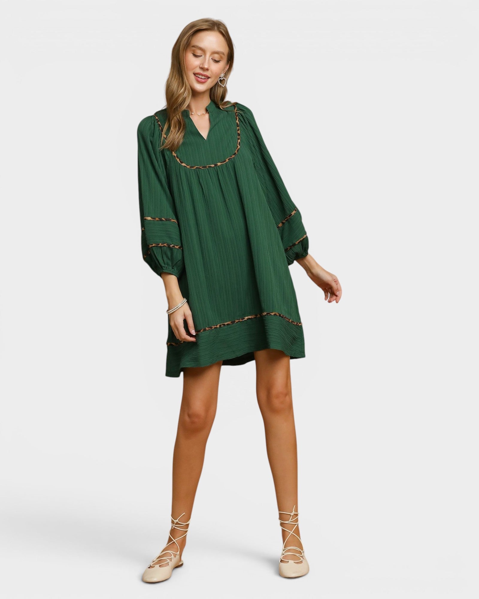 Model wearing a Beach Rose Co. palm green mini dress with balloon sleeves, leopard-print trim, and a split neckline.