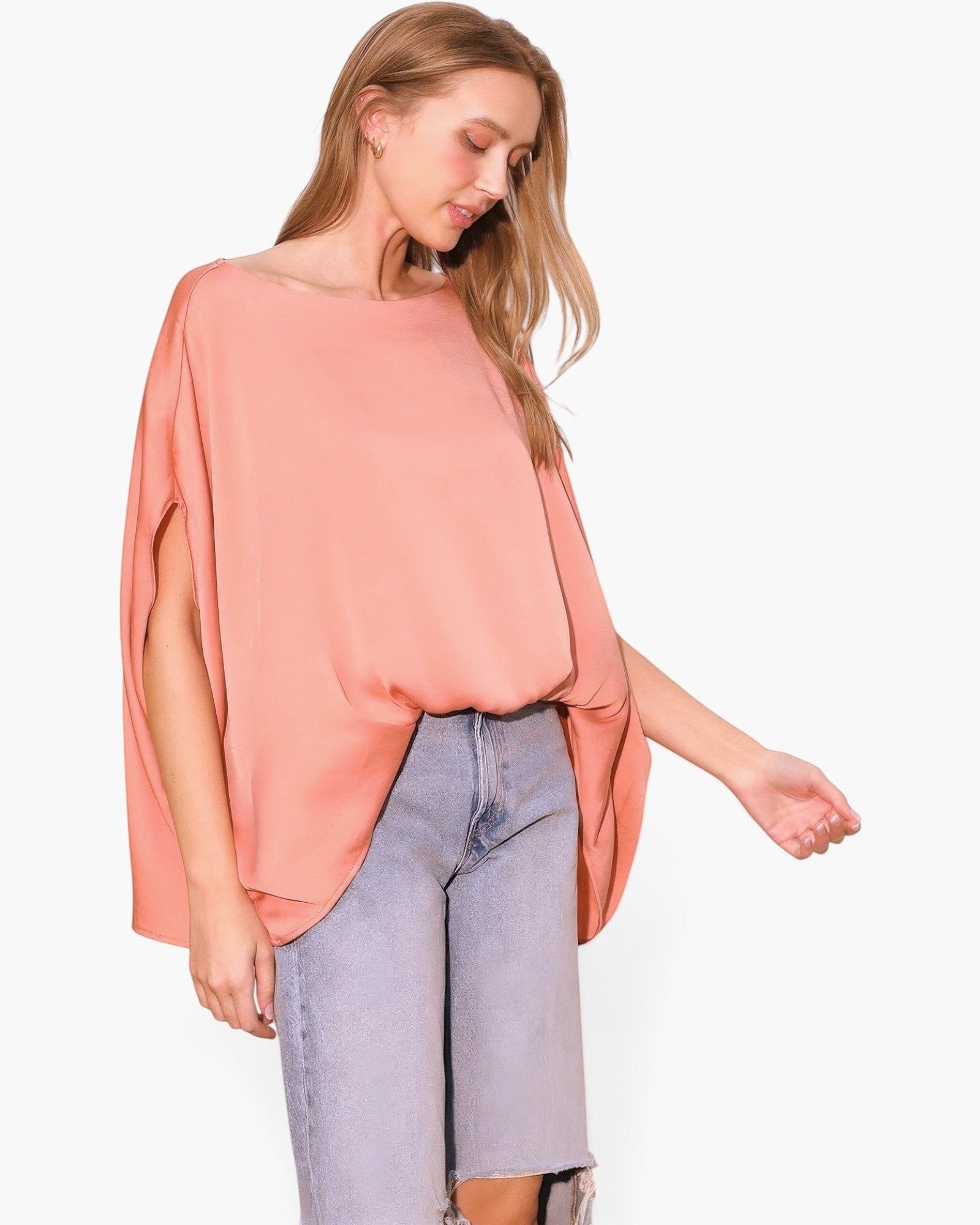 Model wearing a Beach Rose Co. peach washed poly silk caftan top with a boat neckline and flowy sleeves.