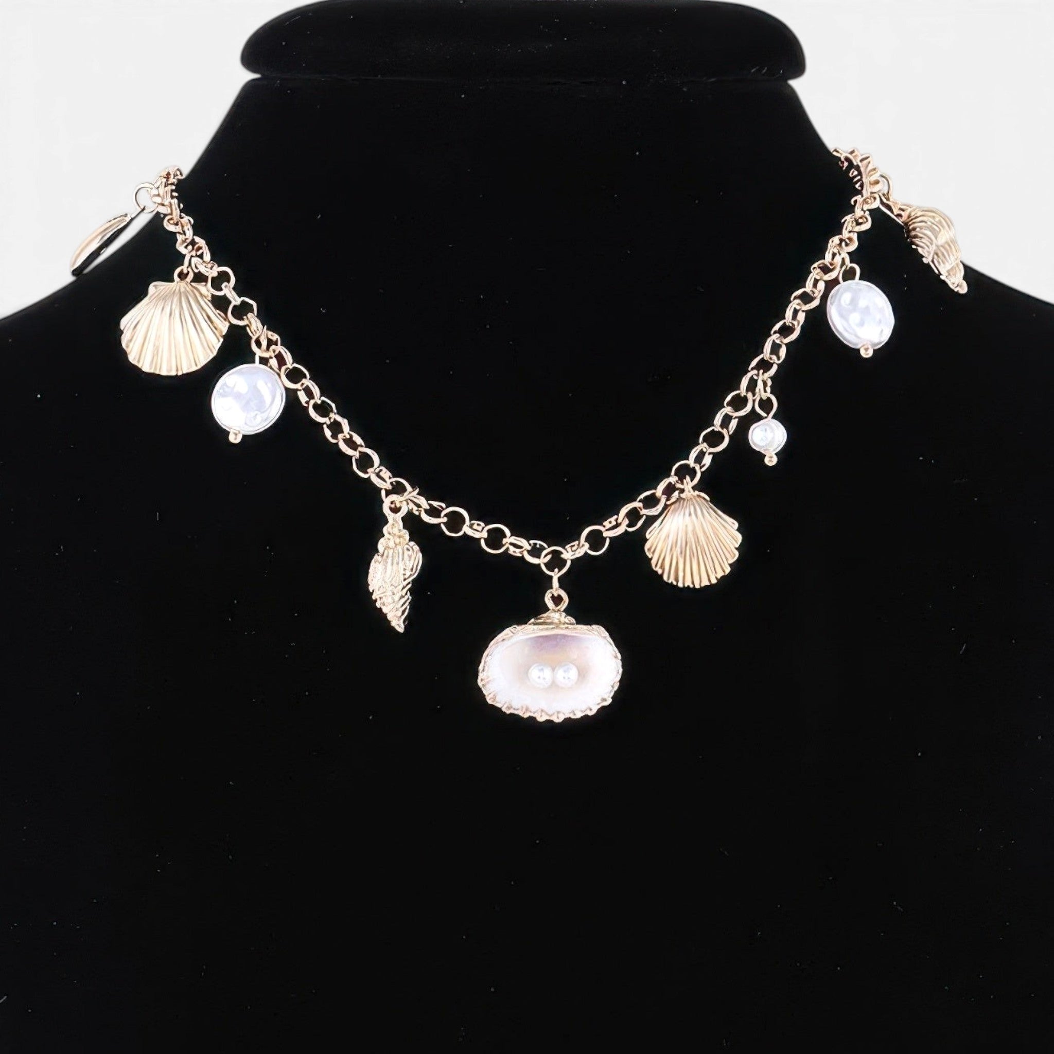 Beach Rose Co. gold chain necklace featuring delicate white pearls and textured shell charms on a black display bust