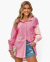 Beach Rose Co. pink color block button down blouse with cuffed sleeves worn by a smiling woman with denim shorts