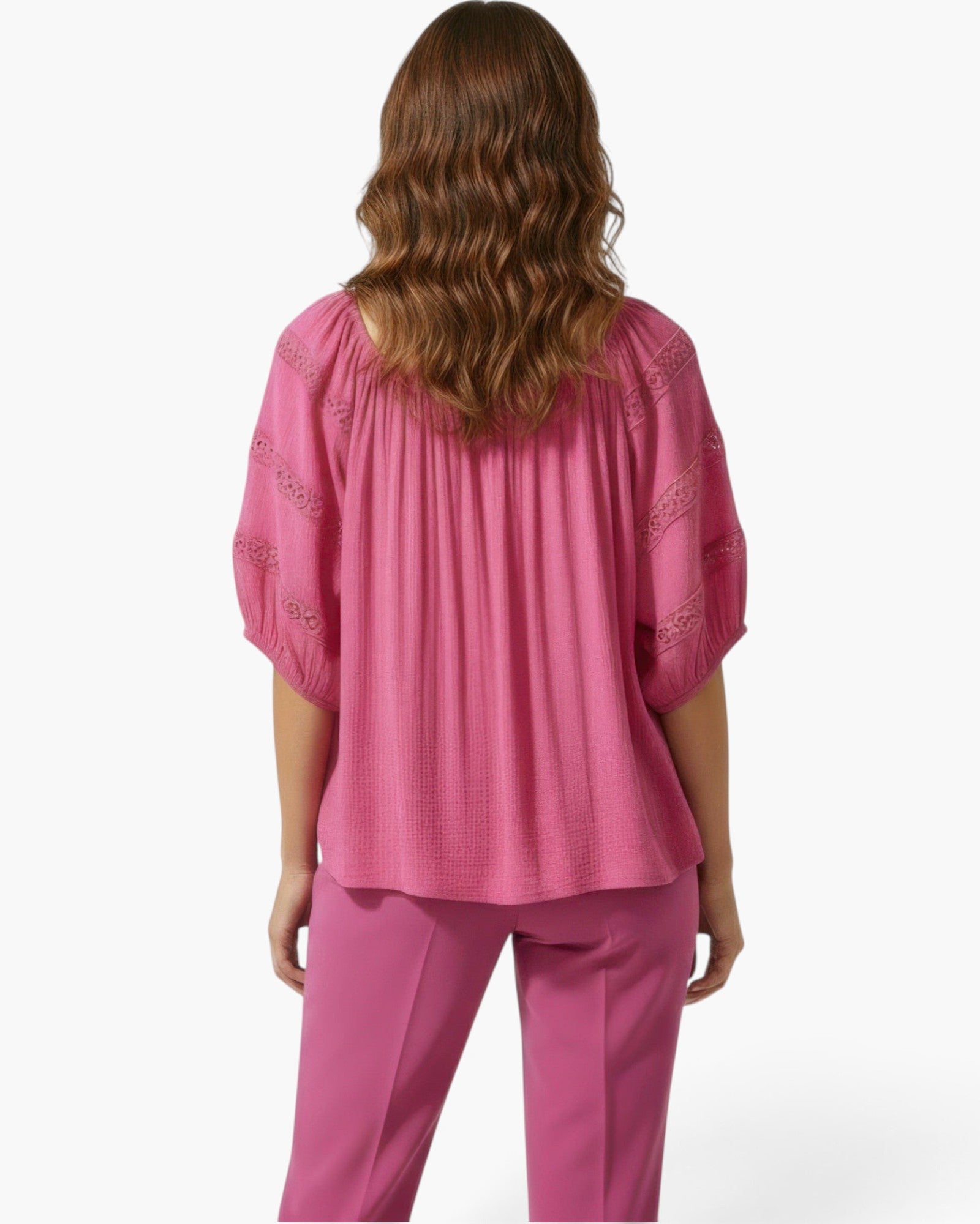 Beach Rose Co. pink short sleeve blouse with crochet sleeve detail and scoop neckline worn by a woman from behind