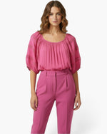 Beach Rose Co. pink short sleeve blouse with a scoop neckline and delicate crochet sleeve detailing on a model.