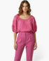 Beach Rose Co. pink short sleeve blouse with a scoop neckline and delicate crochet sleeve detailing on a model.