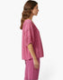 Beach Rose Co. pink short sleeve blouse with scoop neck and delicate crochet sleeve detailing on a model side view