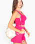 Beach Rose Co. hot pink cropped tank and drawstring shorts set worn by a woman with a white backpack