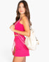 Model wearing a Beach Rose Co. hot pink cropped tank and drawstring shorts set with a white chain-strap backpack.
