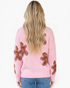 Beach Rose Co. pink crewneck sweater with an allover gingerbread man pattern and red scarf details, back view.