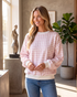 Beach Rose Co. pink and white gingham sweatshirt with balloon sleeves and white ribbed trim worn by a smiling woman.