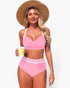 Beach Rose Co. pink high-waisted bikini with cross-front top and white contrasting trim worn by a woman with a sun hat.