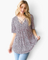 Beach Rose Co. pink leopard print babydoll top with a crisscross V-neckline and short sleeves on a smiling model