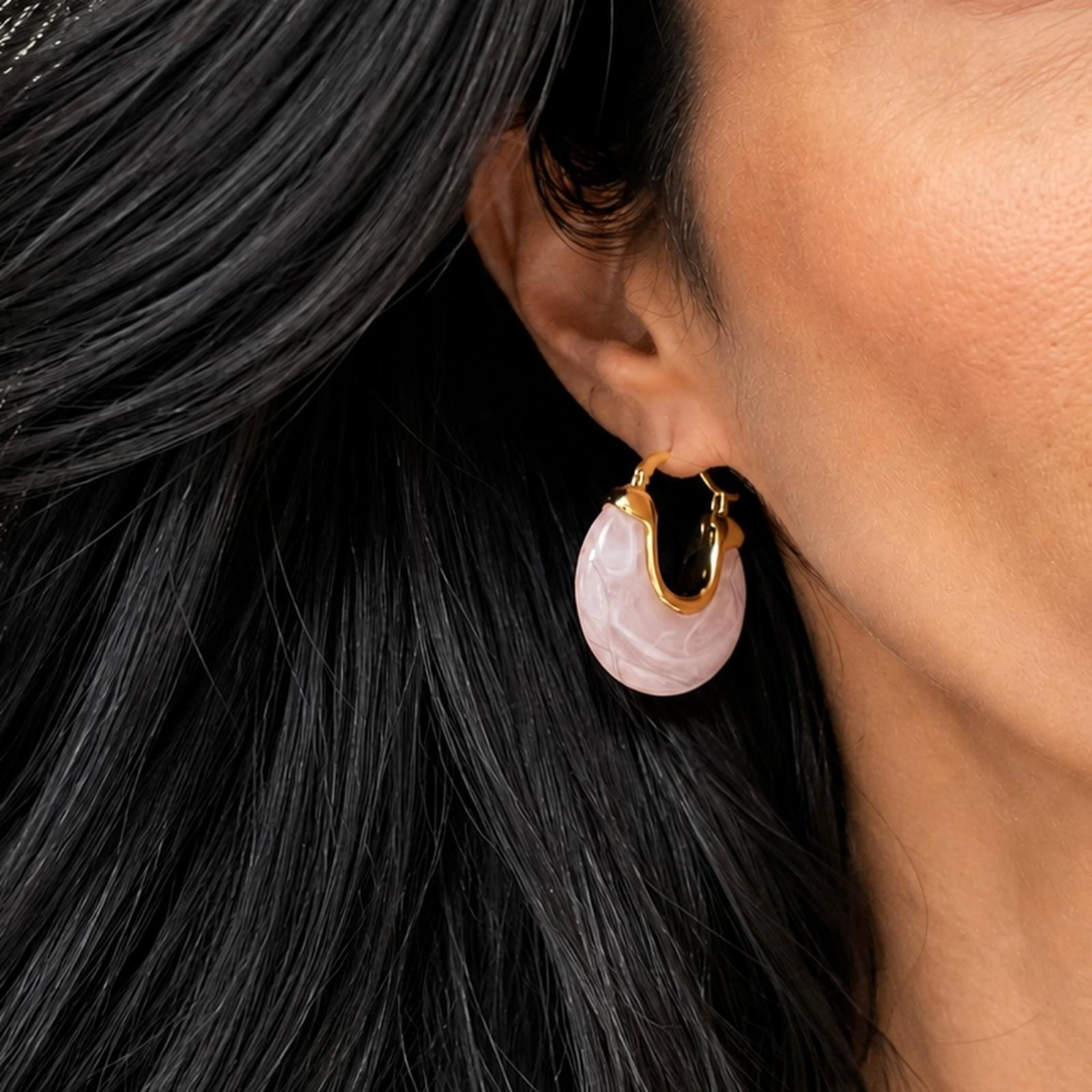 Beach Rose Co. marbled pink resin hoop earrings with 18K gold filled metal frames worn on a model