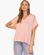 Beach Rose Co. model wearing a light pink washed poly silk V-neck tee with a relaxed fit and cuffed short sleeves.