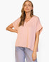 Beach Rose Co. model wearing a light pink washed poly silk V-neck tee with a relaxed fit and cuffed short sleeves.