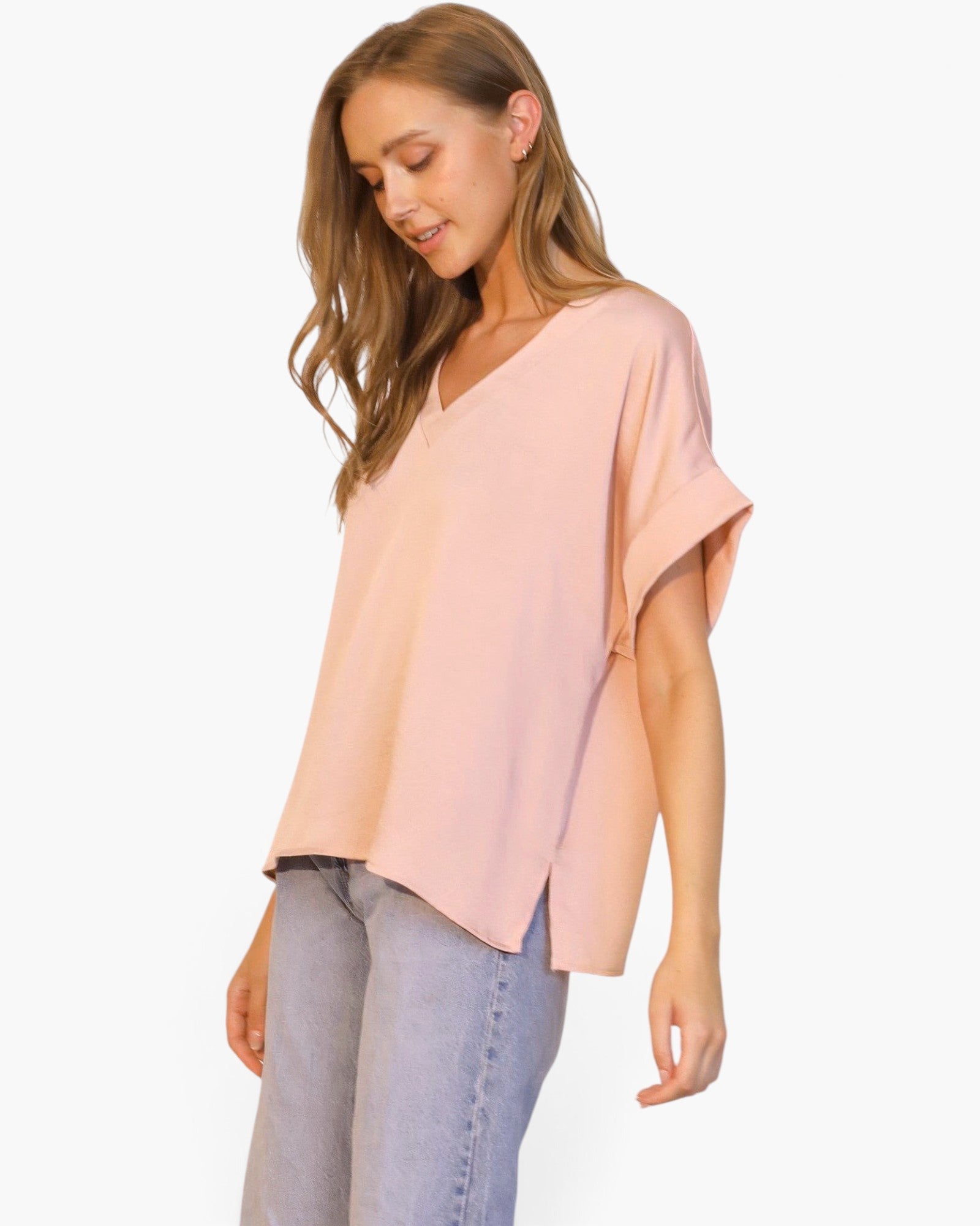 Beach Rose Co. model wearing a light pink washed poly silk V-neck tee with cuffed sleeves and a relaxed fit.