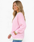 Beach Rose Co. pink sweatshirt with green and white striped ribbed trim and dropped shoulders on a smiling model