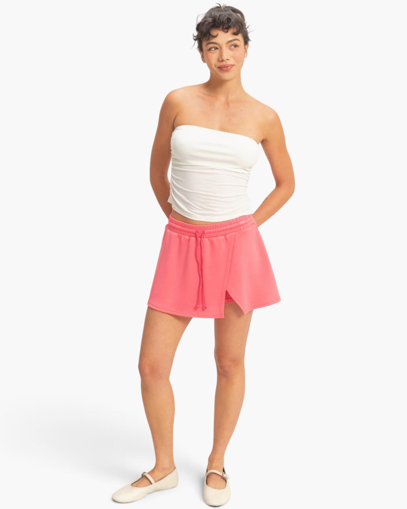 Beach Rose Co. pink wrap front skort with elastic drawstring waist and built-in shorts on a model in a white top
