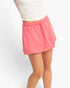 Beach Rose Co. pink wrap front skort with an elastic drawstring waistband and built-in shorts on a model.