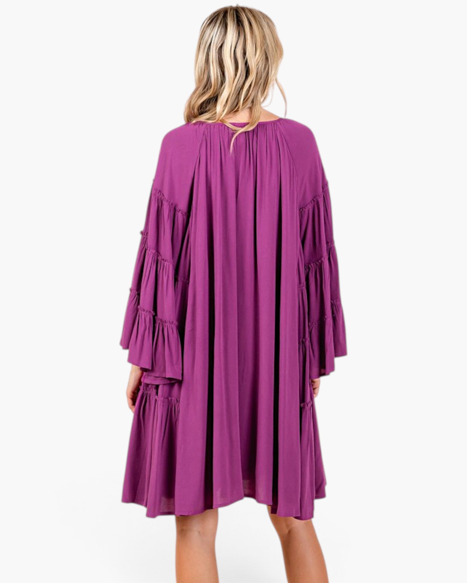 Back view of a Beach Rose Co. plum babydoll dress with tiered bell sleeves and gathered detailing on a blonde model.
