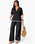 Beach Rose Co. plus size black two-piece set with white ruffle trim, v-neck top, and wide-leg trousers on a model.