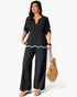 Beach Rose Co. plus size black two-piece set with white ruffle trim, v-neck top, and wide-leg trousers on a model.