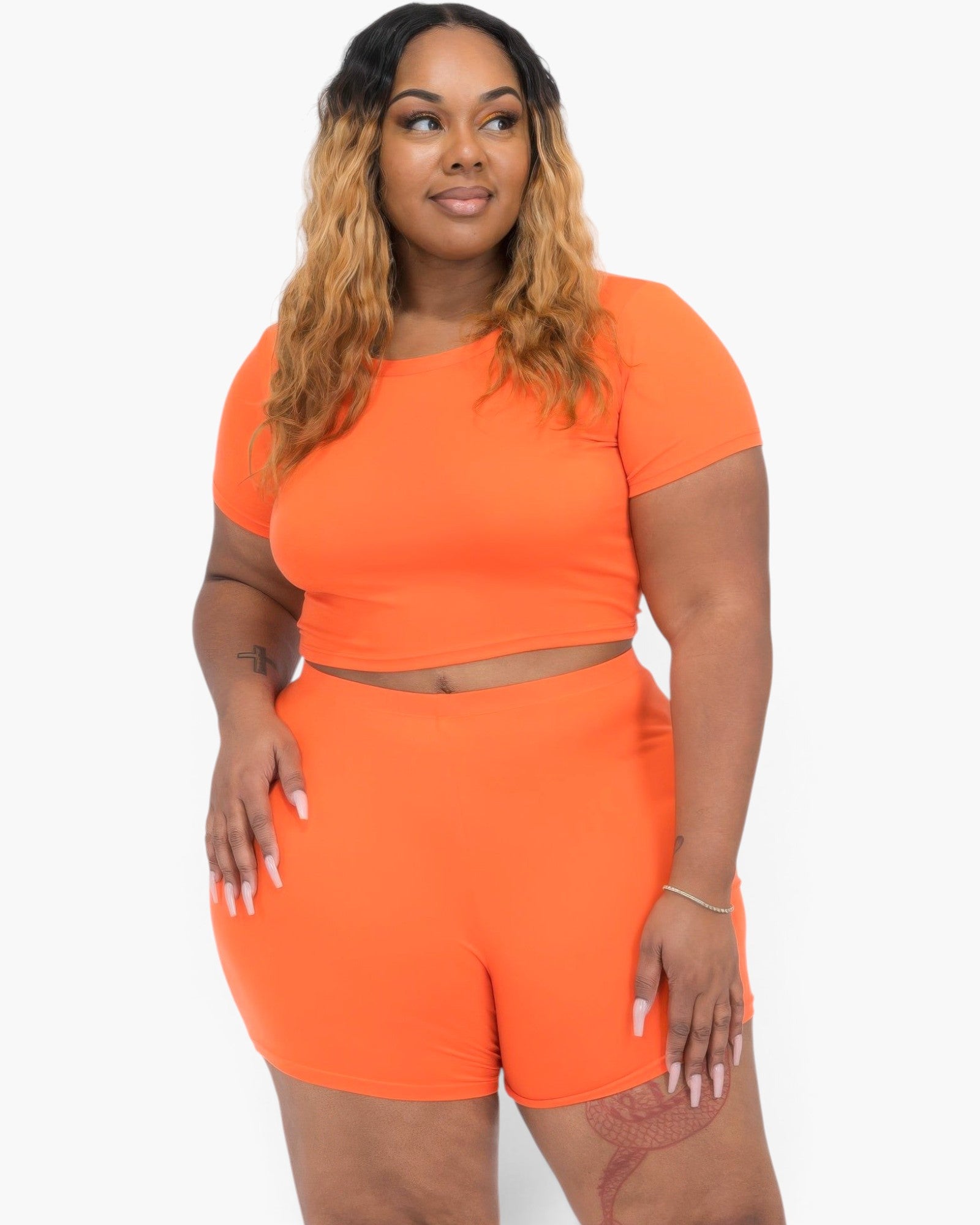 Beach Rose Co. plus size orange short sleeve crop top and matching shorts set on a model with long wavy hair.