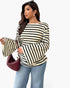 A woman modeling a cream and black horizontally striped long-sleeve top with dramatic bell sleeves, paired with light blue jeans and holding a burgundy quilted handbag against a plain white background.