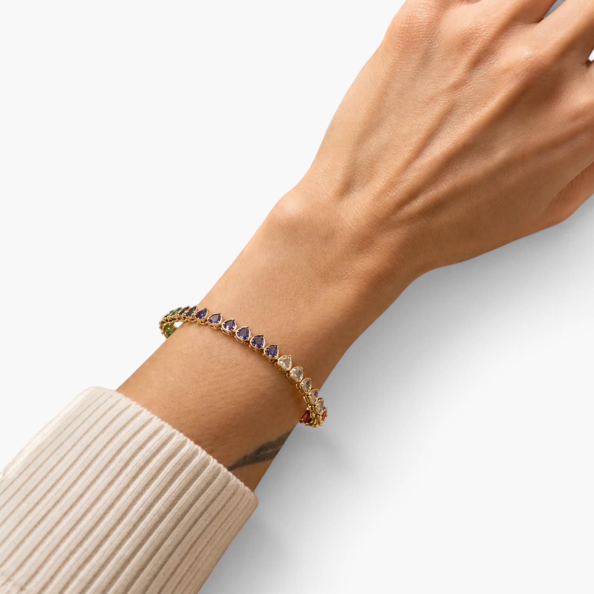 Beach Rose Co. gold tennis bracelet featuring colorful heart-shaped cubic zirconia stones worn on a woman's wrist.