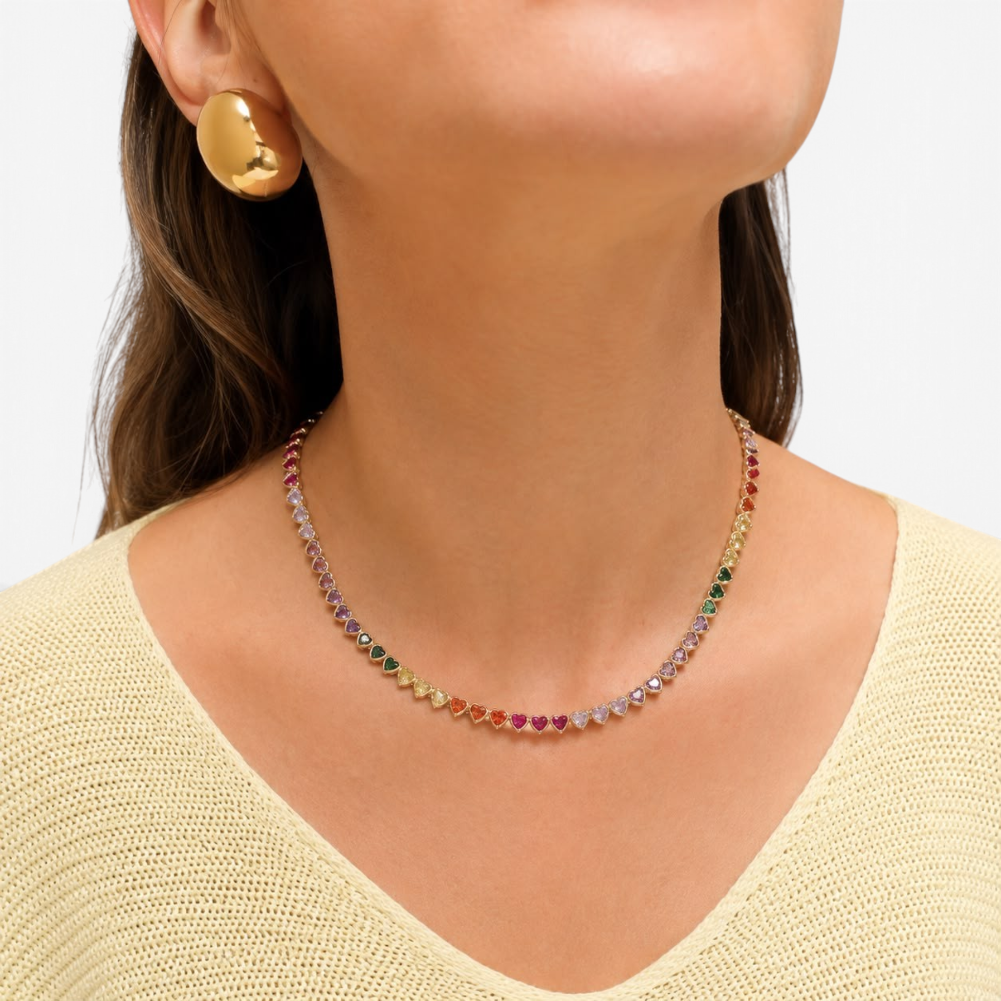 Beach Rose Co. rainbow heart-shaped cubic zirconia tennis necklace worn on a model with a yellow sweater.