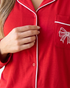 Beach Rose Co. red pajama top with white piping, notched collar, and a white embroidered bow on the chest pocket.
