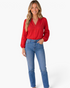 Beach Rose Co. red button-front blouse with crochet sleeve panels and billowy sleeves worn with blue denim jeans.