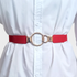 Beach Rose Co. red slim elastic waist belt with an asymmetric gold-tone double-ring buckle worn over a white shirt.