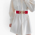 Beach Rose Co. red elastic waist belt with a gold-toned double-circle alloy buckle worn over a white shirt dress.