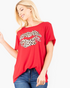 Beach Rose Co. red short-sleeve graphic tee with a leopard-print lips design worn by a smiling blonde woman.