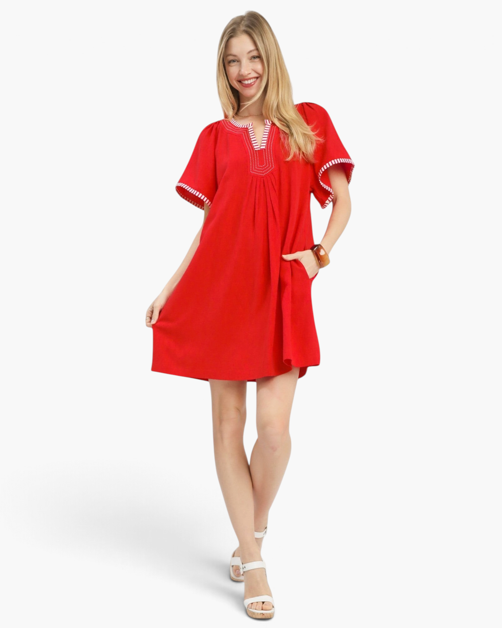 Beach Rose Co. red linen-cotton mini dress with flutter sleeves, white striped trim, and pockets on a smiling model.