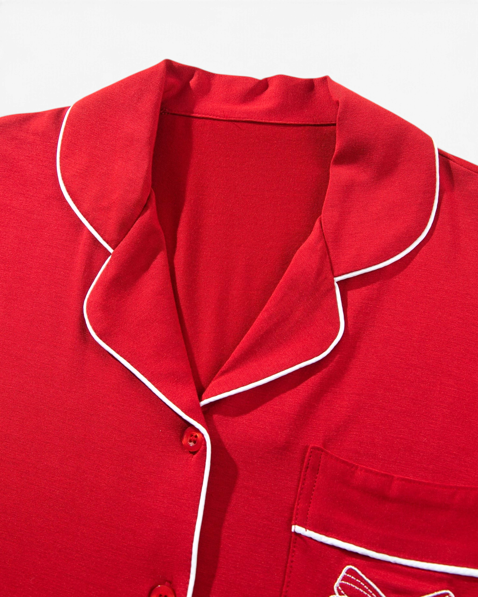 Beach Rose Co. red pajama top with white piping, notched collar, and a bow-detailed chest pocket.