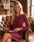 Beach Rose Co. red plaid mini dress with bow-front ties and long puff sleeves worn by a woman in a leather chair