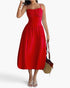 Beach Rose Co. red sleeveless A-line dress with a ruched bust, worn by a model with a straw handbag and sandals.