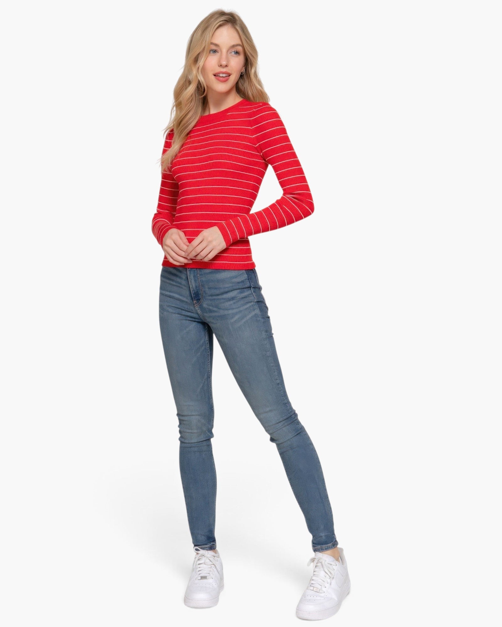 Beach Rose Co. model wearing a red and white striped long sleeve crew neck sweater with blue jeans and white sneakers.