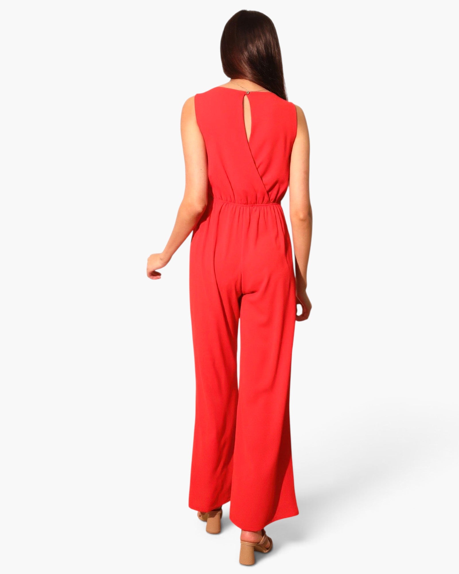 Back view of a woman wearing a red Beach Rose Co. textured wide-leg jumpsuit with a keyhole back detail.