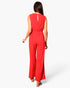 Back view of a woman wearing a red Beach Rose Co. textured wide-leg jumpsuit with a keyhole back detail.