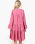 Back view of a Beach Rose Co. rose pink tiered shift dress with long bell sleeves and gathered detailing.