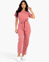 Model wearing a Beach Rose Co. rosewood pink relaxed rib knit jumpsuit with a tie waist and short sleeves.