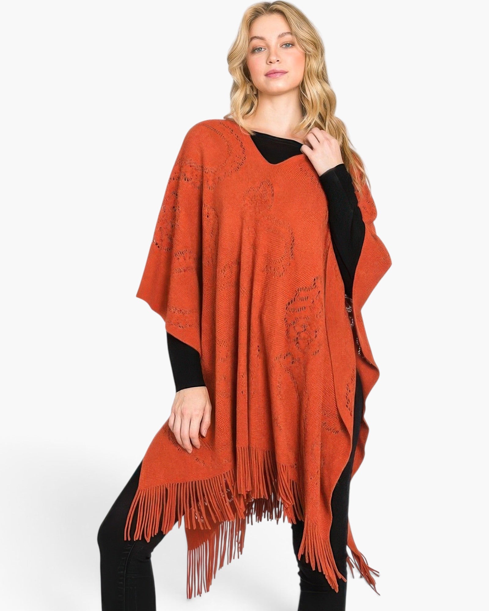 Beach Rose Co. rust orange acrylic poncho with paisley pattern and fringe hem worn by a blonde model
