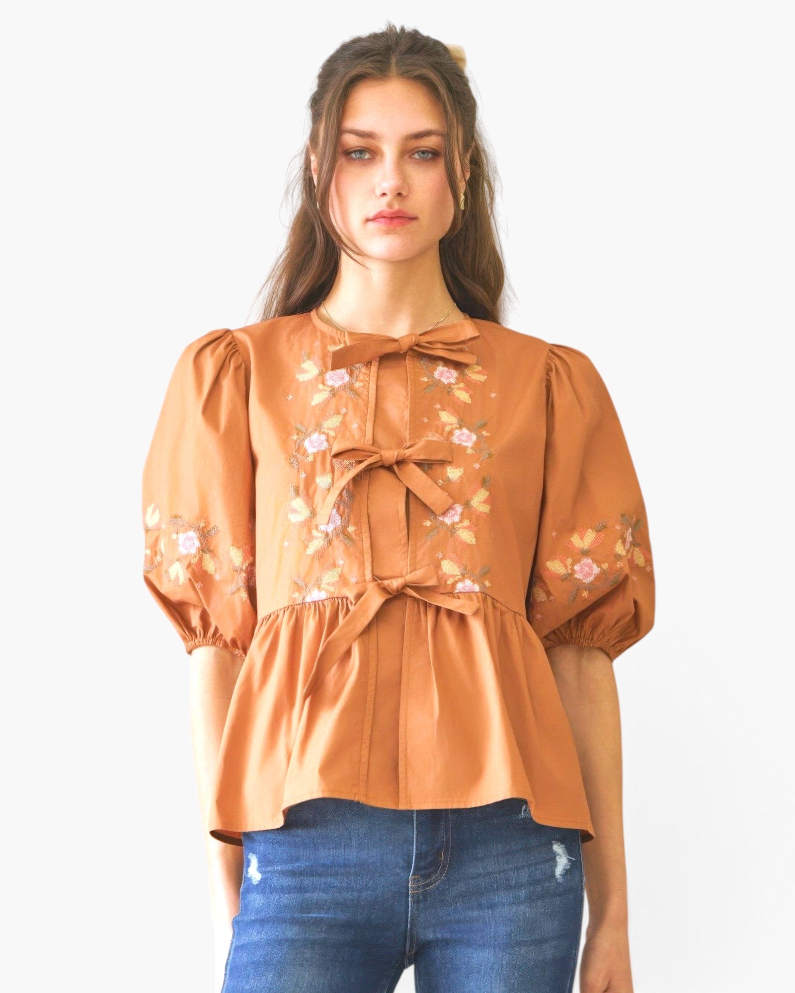 Beach Rose Co. rust-coloured poplin blouse with front ribbon ties, floral embroidery, and puff sleeves on a model.