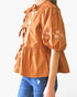 Beach Rose Co. rust-colored poplin blouse with front ribbon ties, puff sleeves, and delicate floral embroidery.