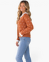 Beach Rose Co. rust cardigan with white knit motifs, scalloped collar, and ribbed cuffs worn with blue jeans