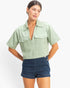 Beach Rose Co. sage green cotton collared V-neck top with short sleeves and two front flap pockets on a model