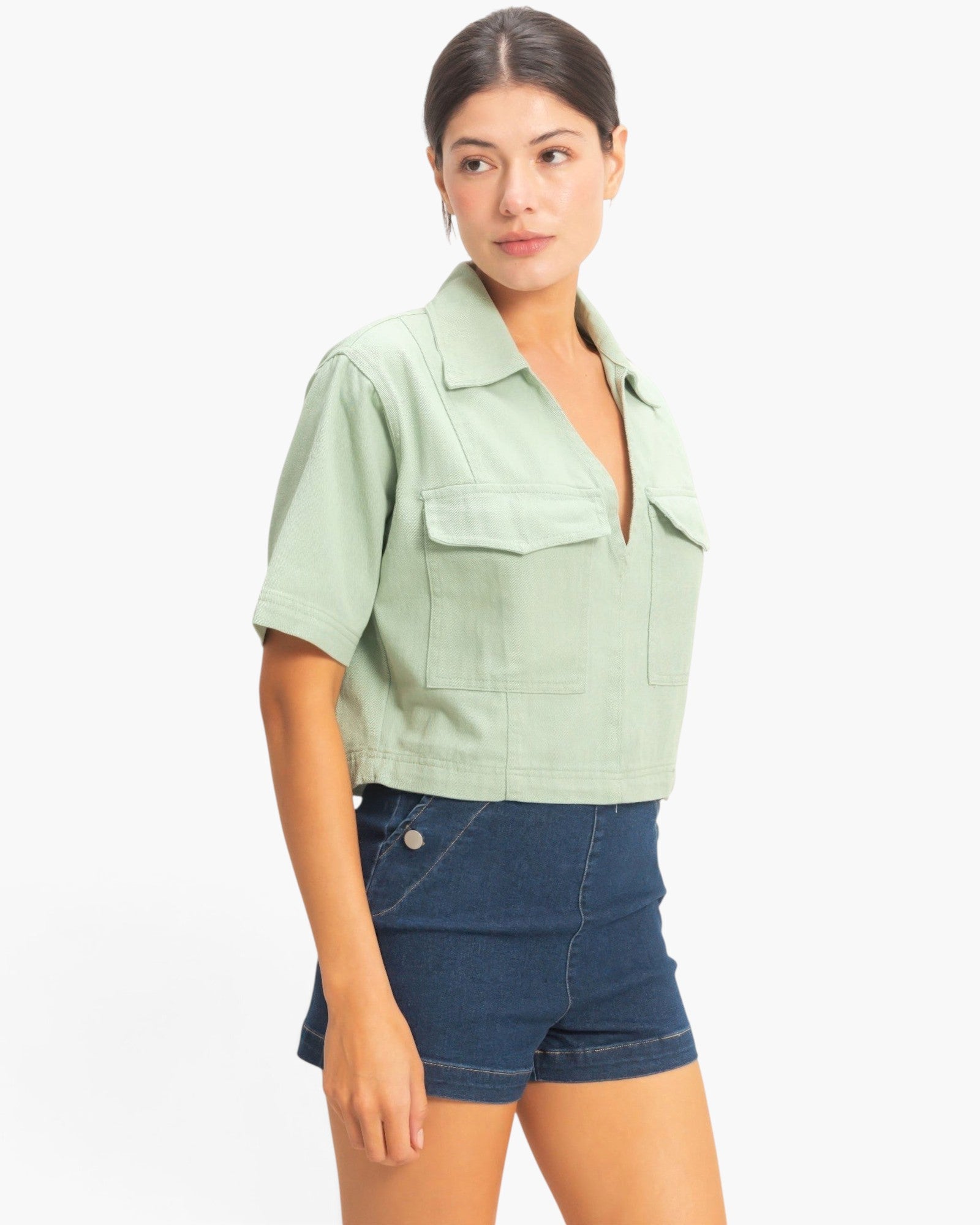 Beach Rose Co. sage green cotton cropped top with a collared V-neck and two front flap pockets on a female model